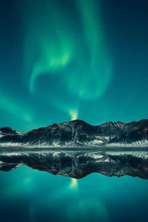 Aurora Borealis over a mountain range reflected in water