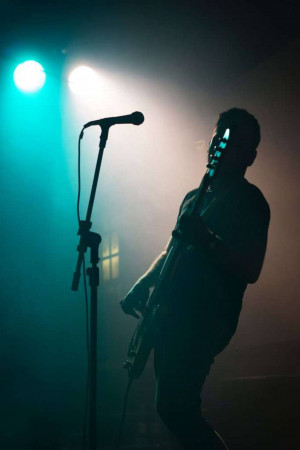 A silhouetted figure playing the saxophone on a stage with dramatic lighting.