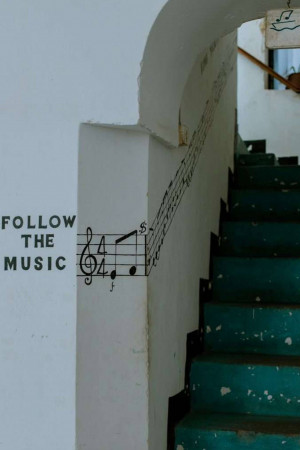 A staircase with musical notes and the phrase 'Follow the Music' painted on the wall.