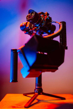 A professional camera mounted on a gimbal stabilizer with dramatic lighting.