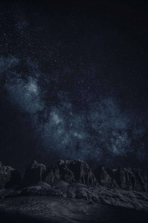 Night landscape with the Milky Way galaxy visible above silhouetted mountains.