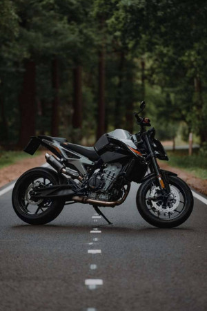 Black KTM motorcycle parked on a road through a forest
