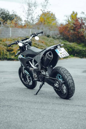A black supermoto motorcycle parked on asphalt.