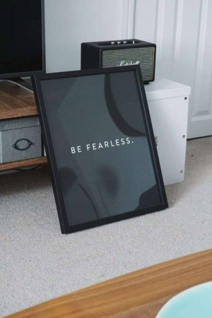 Framed 'Be Fearless' print with a vintage radio and TV in the background