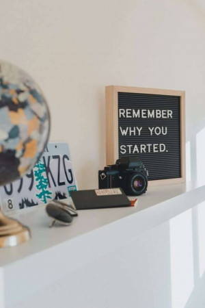 A motivational quote displayed on a letter board with a vintage camera and globe.