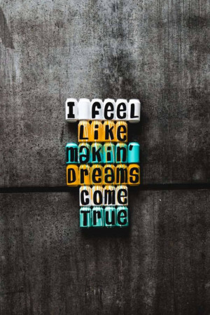 Letter blocks spelling out 'I Feel Like Makin' Dreams Come True' against a dark textured background.