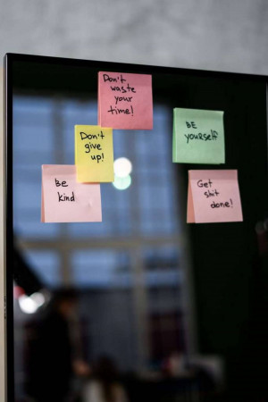 Close-up of a computer monitor with colorful sticky notes displaying motivational messages.