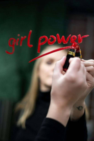 Woman holding red lipsticks with 'girl power' written in lipstick on glass