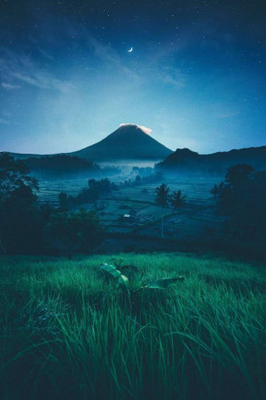 Night view of Mount Bromo with a crescent moon and starry sky