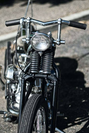 Close-up of a classic black chopper motorcycle's handlebars, headlight, and front fork