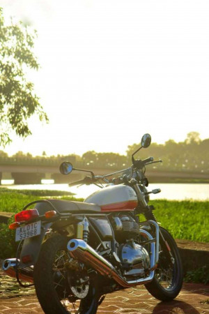 Rear view of a Royal Enfield Classic 350 motorcycle parked by a river during sunset
