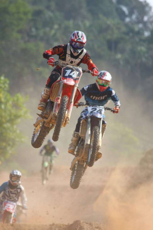 Two motocross riders jumping mid-air during a race
