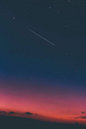 A dark blue and pink night sky with a bright shooting star.