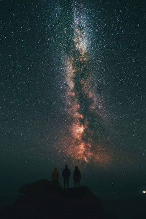 Silhouettes of three people gazing at the Milky Way galaxy