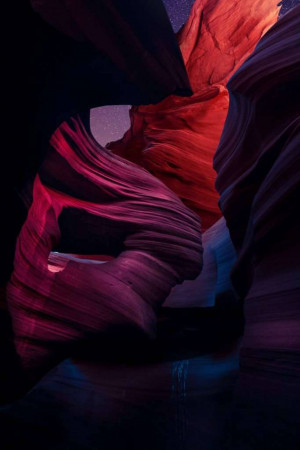 A stunning view inside Antelope Canyon, showcasing swirling sandstone formations illuminated with vibrant red, purple, and blue hues.