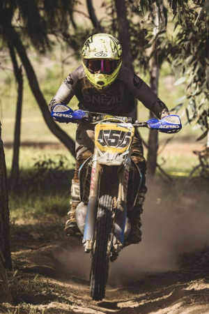 A motocross rider on a dirt bike riding through a dusty trail.