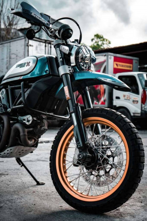 Close-up of a teal and gold Ducati Scrambler Cafe Racer motorcycle