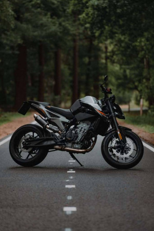 Black KTM motorcycle parked on a road through a forest