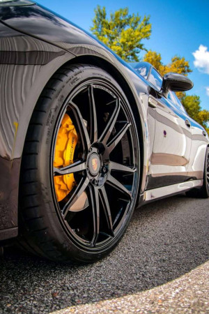 Close-up of a Porsche's wheel, tire, and bright yellow brake caliper.
