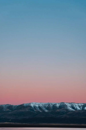Snow-capped mountains silhouetted against a colorful sunset sky