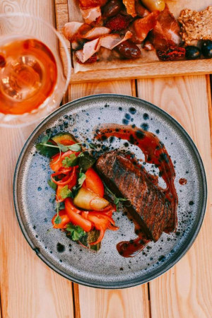 Close-up of a beautifully plated steak with colorful vegetables and a glass of orange juice.