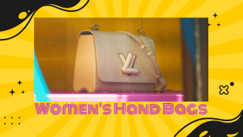 Close-up of a beige Louis Vuitton handbag with a pink strap, displayed in a shop window.