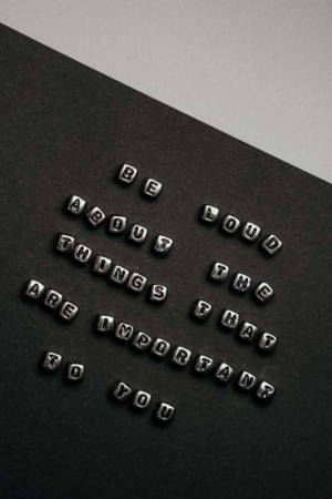 Silver letter beads spelling out an inspirational quote on a black surface.