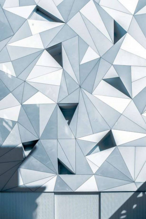 Close-up of a modern building facade with a geometric pattern of triangular panels.
