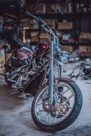 Close-up of a custom chopper motorcycle with a helmet resting on the seat in a garage setting.
