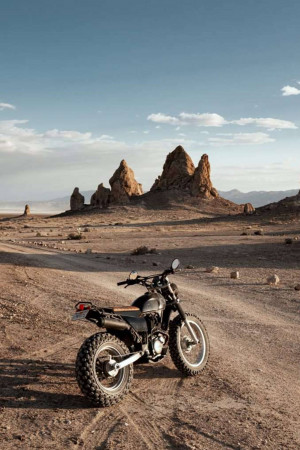 Black motorcycle parked in a desert landscape with rock formations