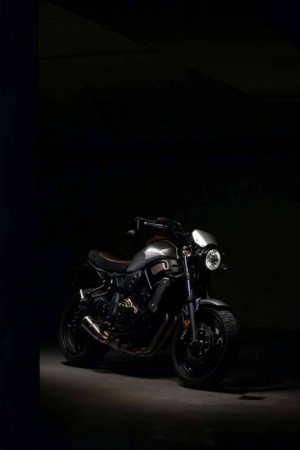 A sleek, dark-colored motorcycle parked in a dimly lit space.