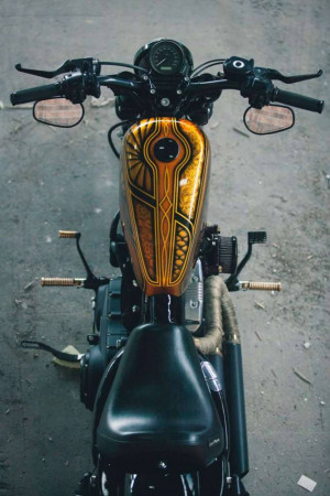 Overhead view of a custom motorcycle fuel tank with intricate gold and black detailing.