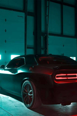 Dark gray Dodge Challenger parked in a dimly lit garage with red taillights