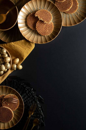Close-up of Dutch stroopwafels, chocolate eggs, and decorative feathers on plates.