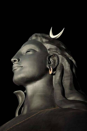 Close-up of a large, dark-colored Shiva statue with a crescent moon on his head.