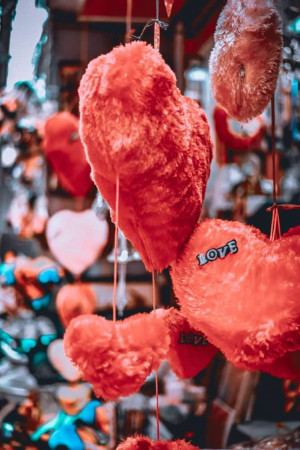 Close-up of red and pink heart-shaped plush toys hanging in a shop