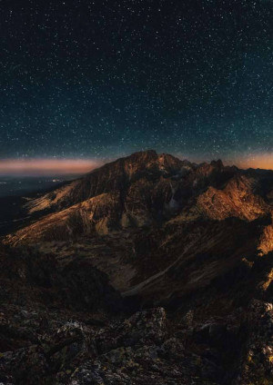 Mountain range silhouetted against a vibrant starry night sky