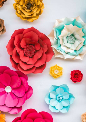 Assortment of vibrant, handmade paper flowers arranged on a white wall.