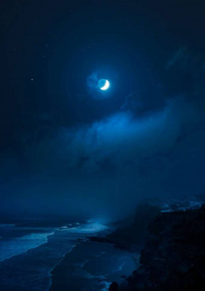Crescent moon shining over a dark ocean and cloudy sky