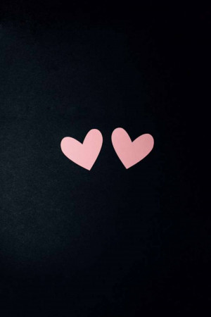 Two pink paper hearts on a black background