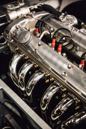 Close-up of a classic car engine with chrome details and red spark plug wires.