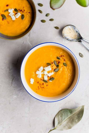 Overhead shot of butternut squash soup in bowls with pumpkin seeds and feta cheese