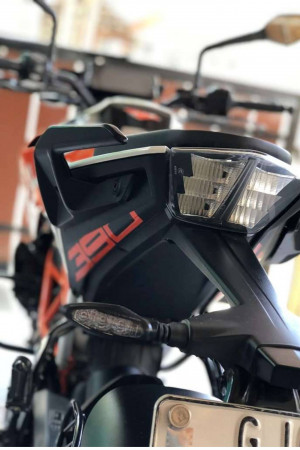 Close-up of the front headlight and dashboard of a black and orange KTM 390 Adventure motorcycle.