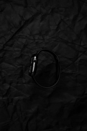Close-up of a black Apple Watch on a black crumpled paper background