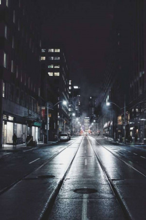 A wet city street illuminated by streetlights at night.