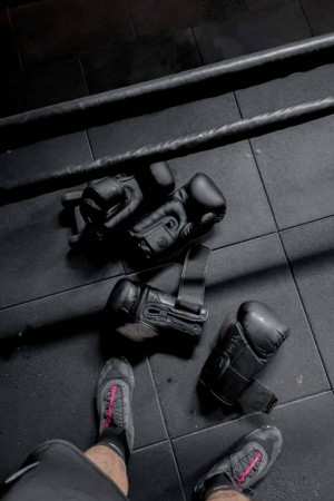 Boxing gloves, hand wraps, and training shoes on a gym floor