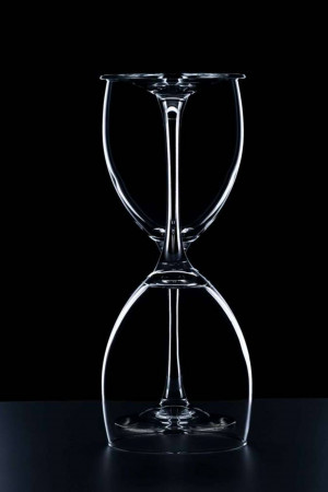 Two wine glasses inverted and joined together, creating an hourglass shape.