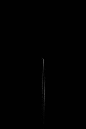A long white contrail from an airplane against a black night sky.