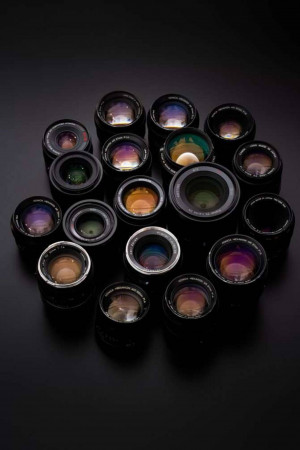 A collection of various camera lenses arranged on a dark surface.