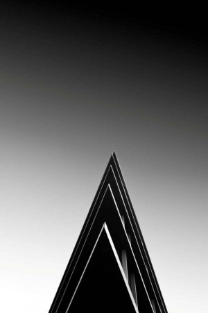 Black and white photograph of a modern building corner pointing upwards